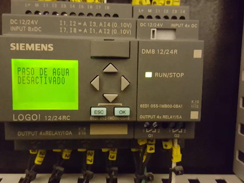 Controlador programable montado en un tablero, con su pantalla y el cableado de entradas y salidas marquillado.